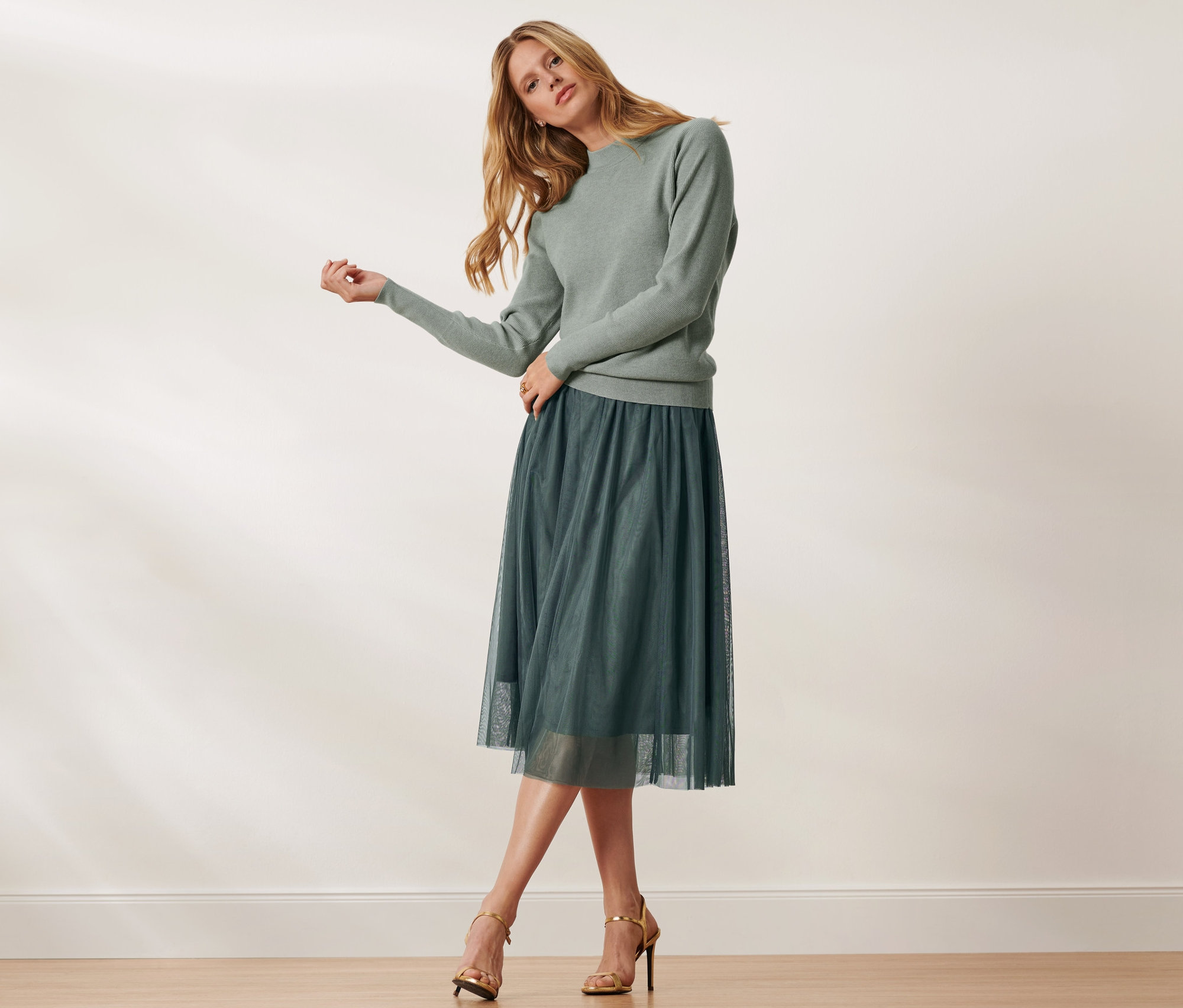 Nő pózol zöld pulóverben és női tüllszoknyában, zöld.