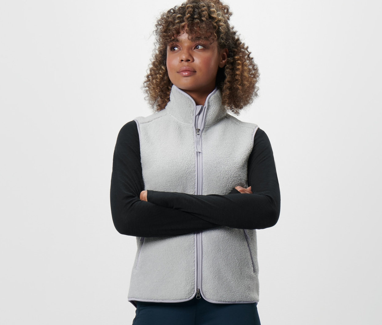 Egy nő keresztbe font karokkal plüssmellényt visel.