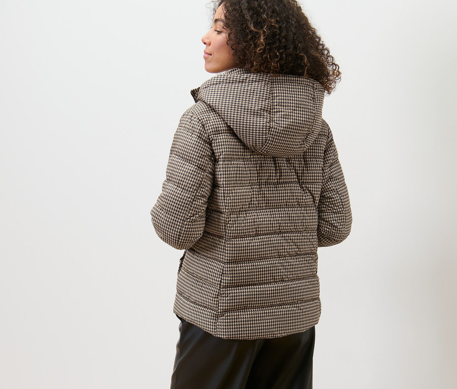 Nő visel egy tyúklábmintás steppelt dzsekit.