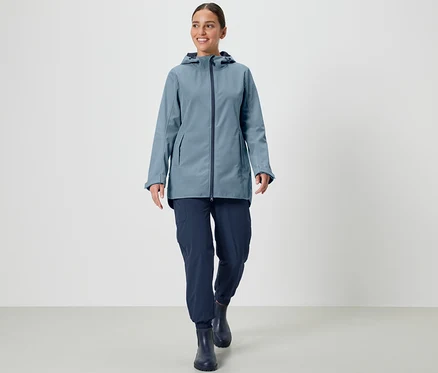 Nő sétál, világoskék softshell dzseki van rajta.