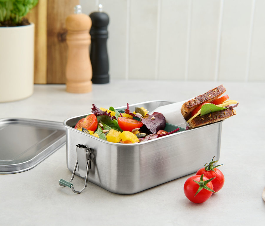 Egy rozsdamentes acélból készült ebédlődoboz paradicsommal, salátával és szendviccsel.