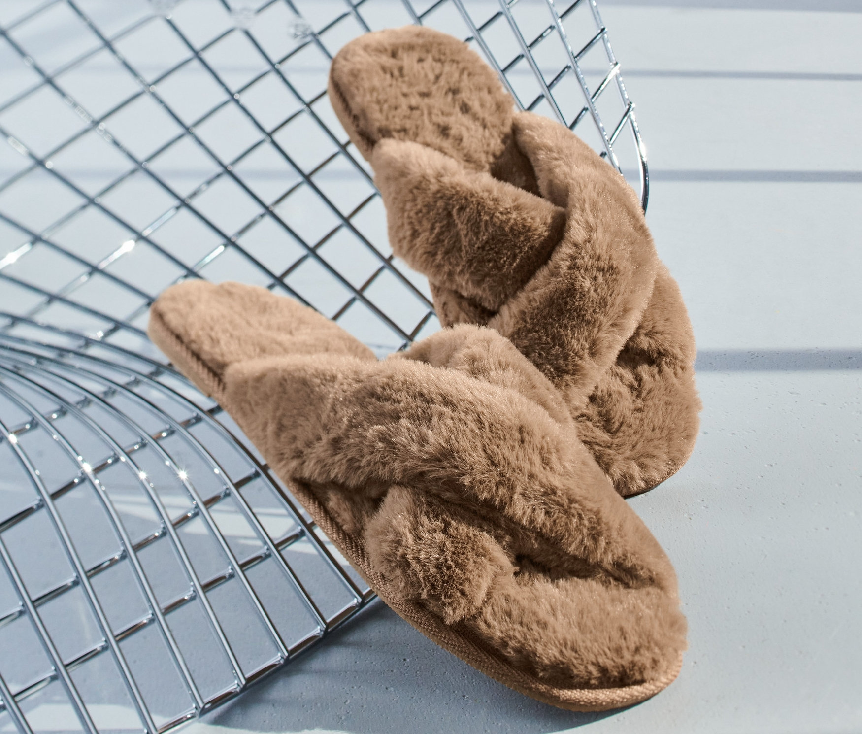 Barna plüss papucsok keresztben egy fémrácson.