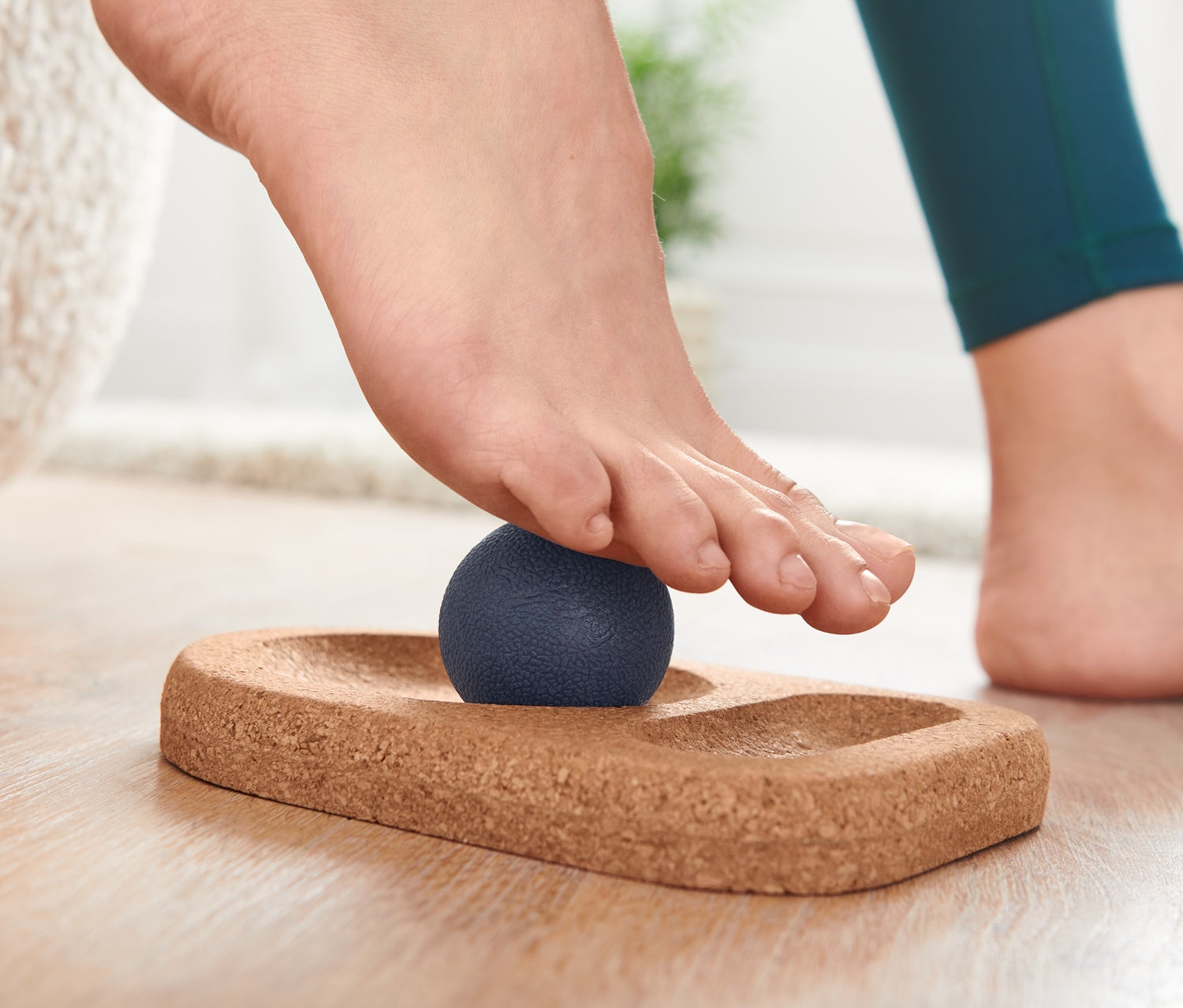 Láb egy talpmasszírozó készleten, kék masszázslabda a parafa alapon.