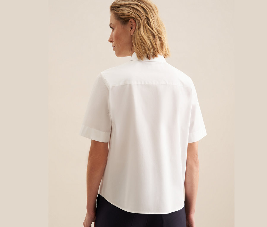Hátulról látható nő fehér Seidensticker rövid ujjú blúzban.
