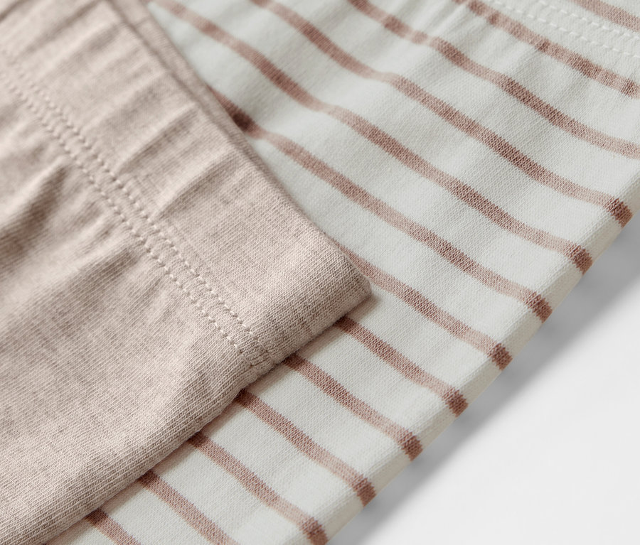 Közelkép 5 gyerekleggingsről, az egyik bézs, a másik barna csíkos.