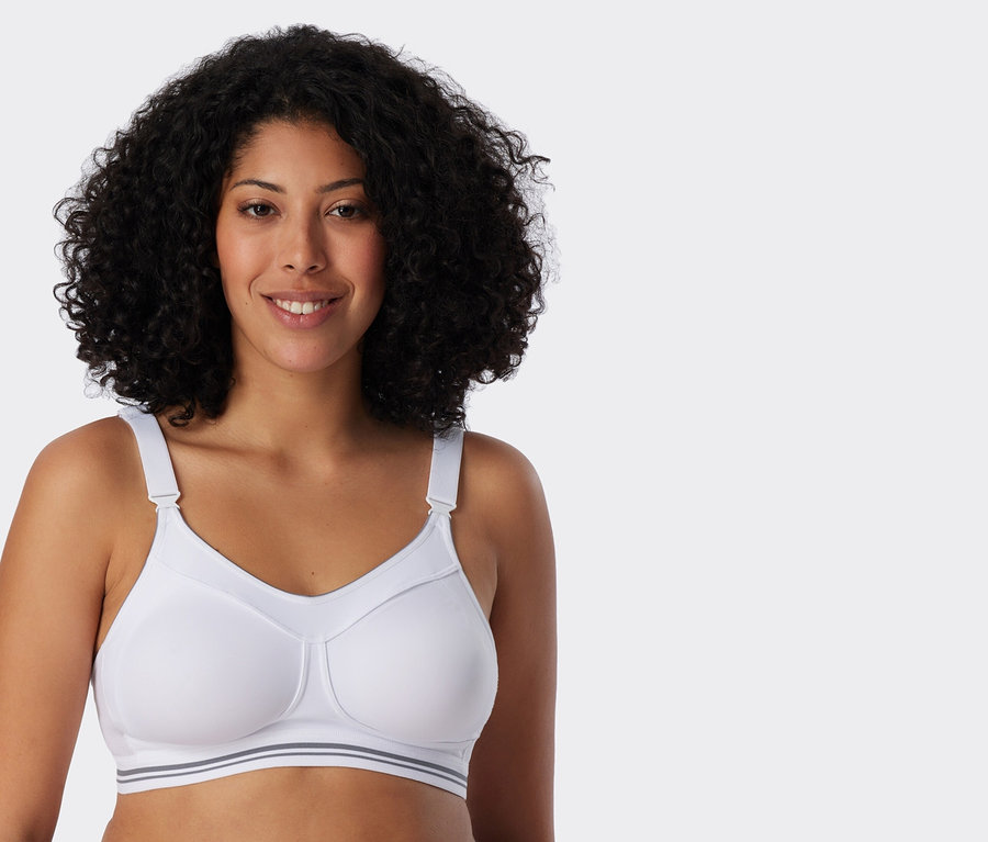 Göndör hajú nő fehér sportmelltartót visel.