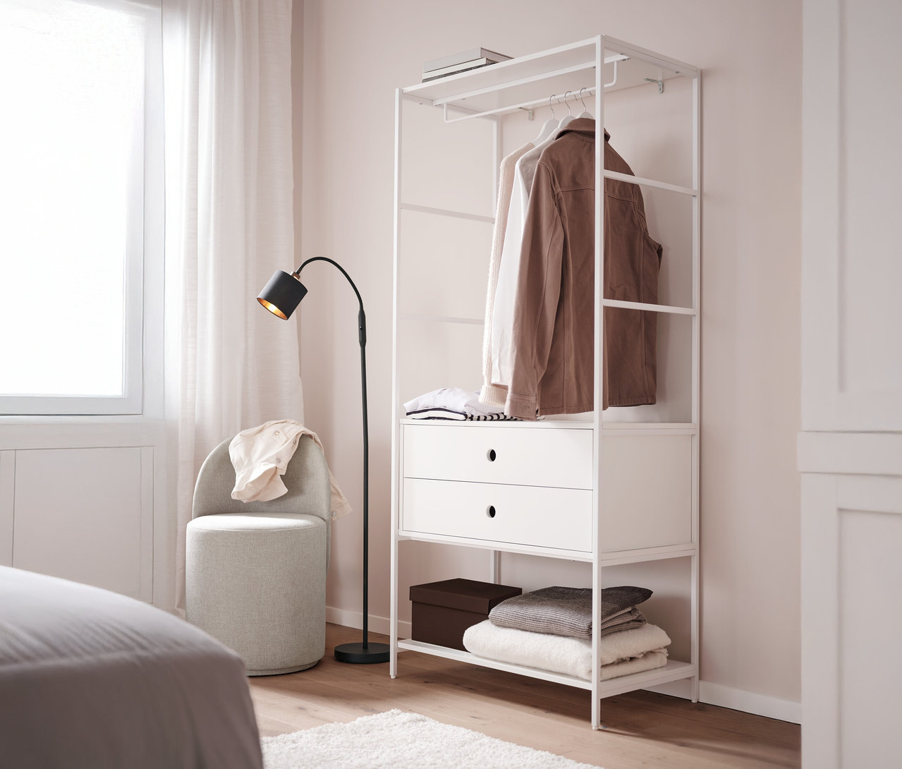 Forgó ülőke háttámlával áll egy fehér »KLAAR« gardrób mellett 2 fiókkal egy hálószobában.