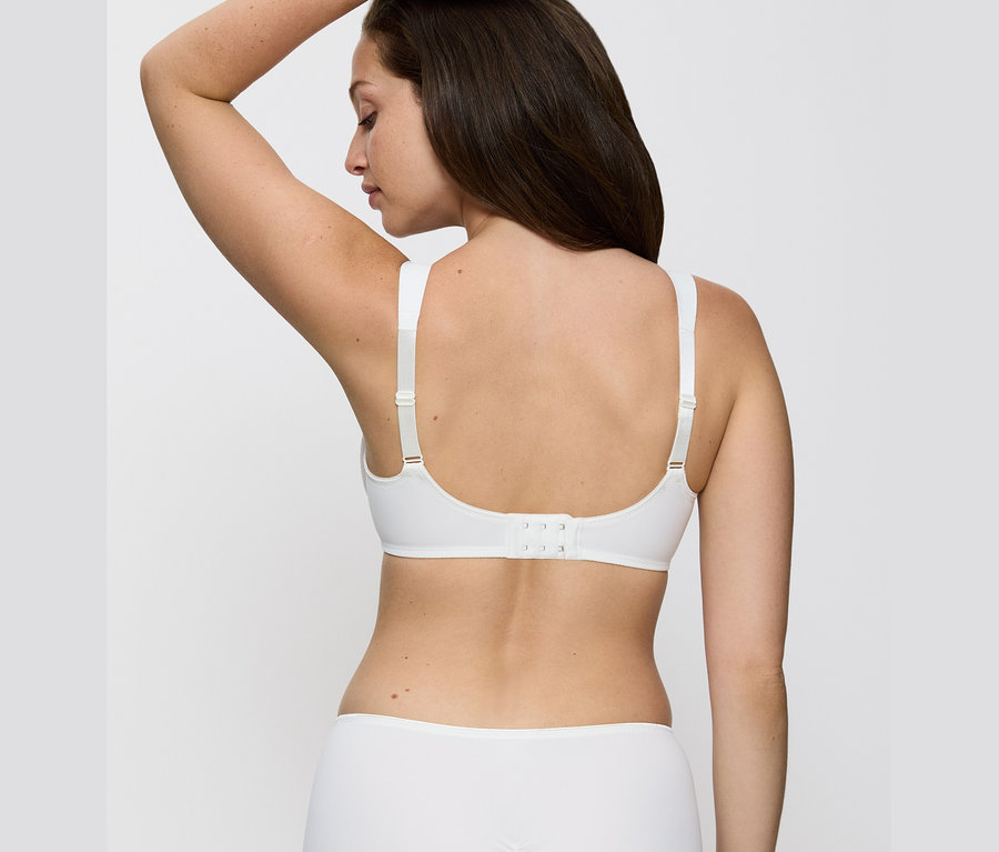 Hátulról látható egy barna hajú nő, aki vanília színű Triumph Essential »Minimizer W X« melltartót visel.