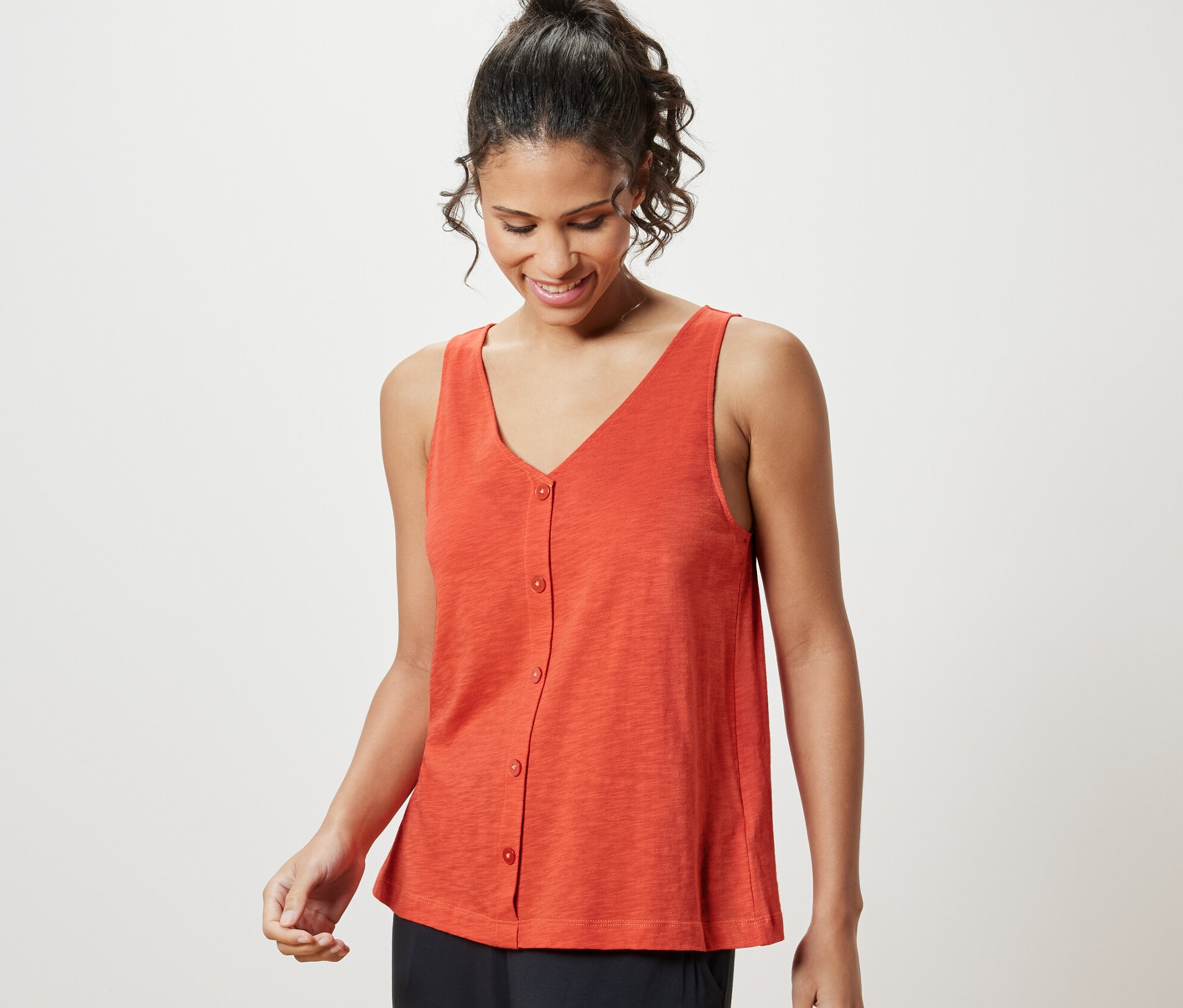 Nő visel egy narancssárga, modálkeverékből készült felsőt.