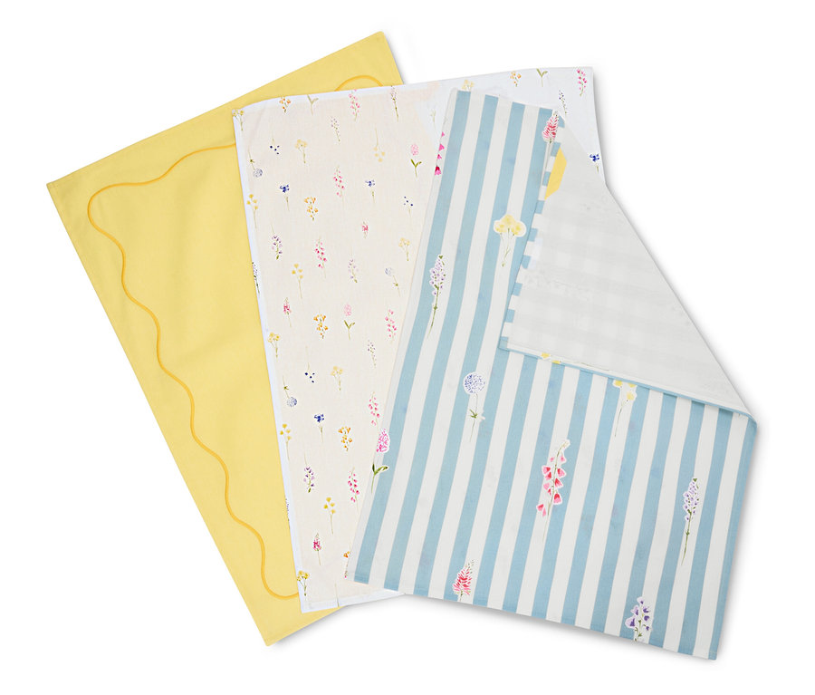 Három kendő fekszik egymáson: egy sárga hullámos széllel, egy krémszínű virágmintával és egy kék-fehér csíkos virágokkal.
