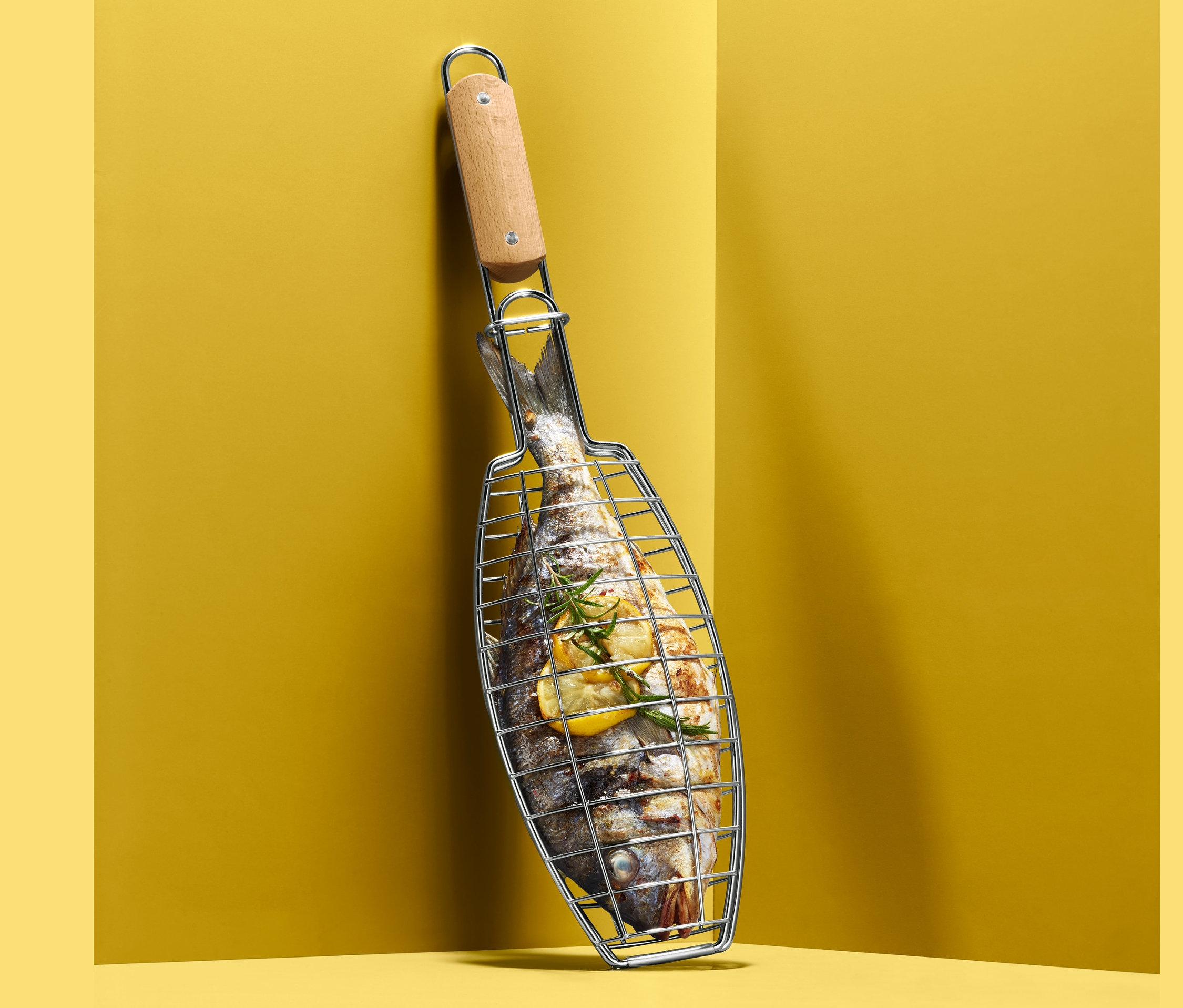 Egy hal a hal- és zöldségsütő grillrácsban, a sárga falnak támasztva.