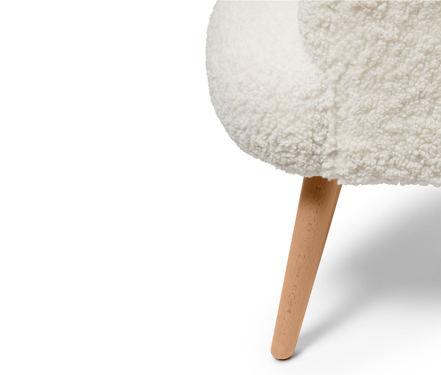 Egy plüss fotel részlete fa lábbal.