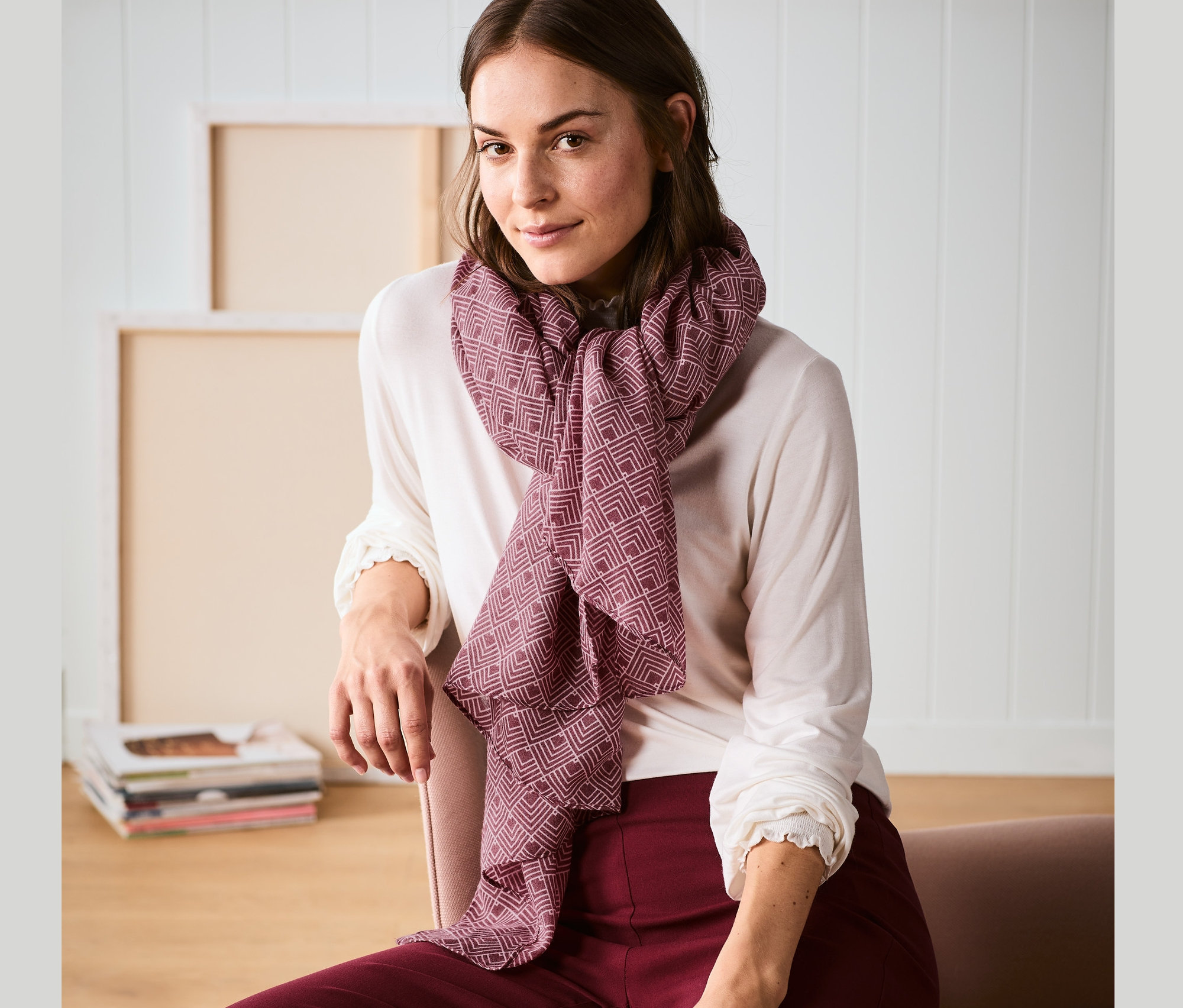 Egy nő ül, és egy mintás, bordó női szövött sálat visel.