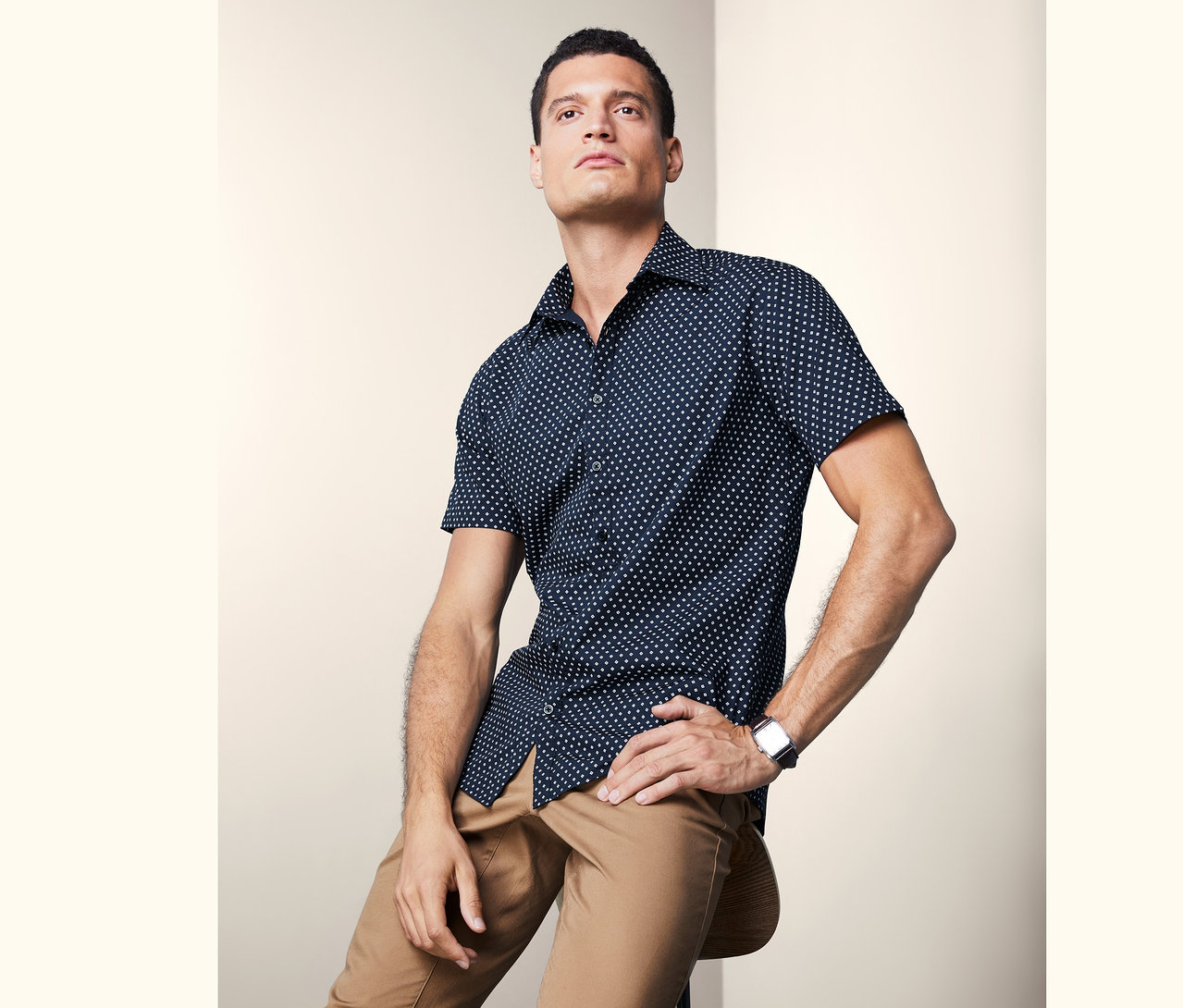 Férfi ül egy széken és rövid ujjú inget visel.