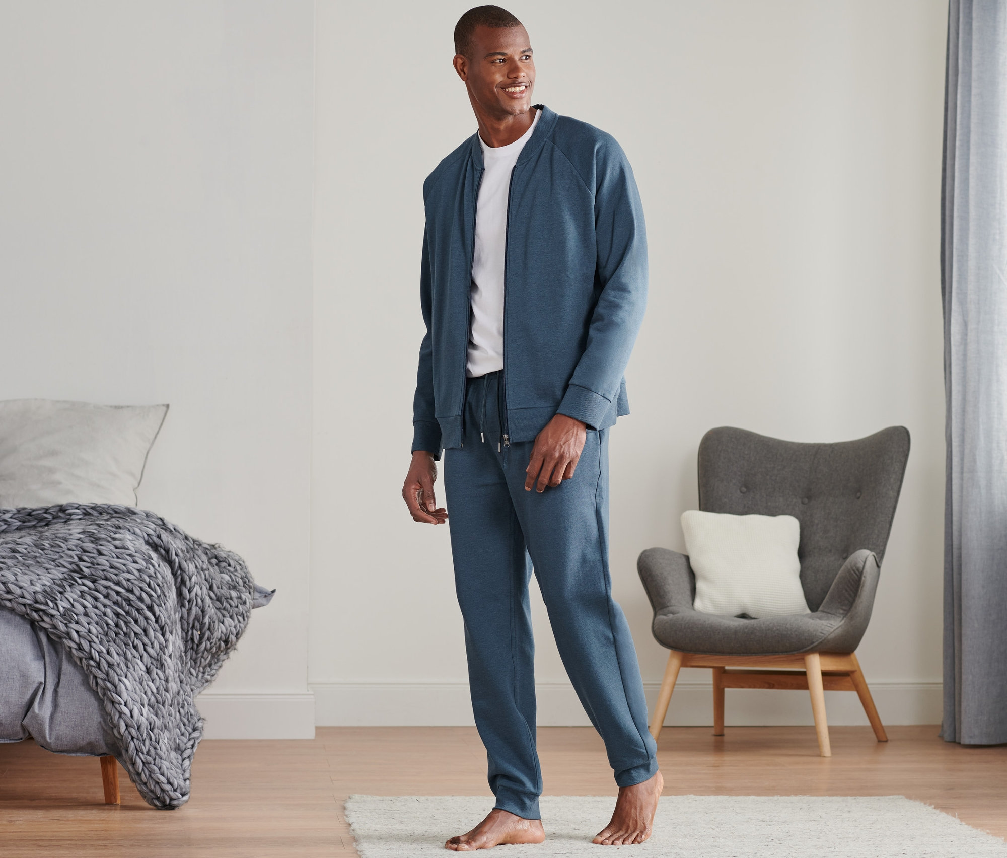 Férfi kék, melírozott férfi szabadidő szettben áll a szobában.