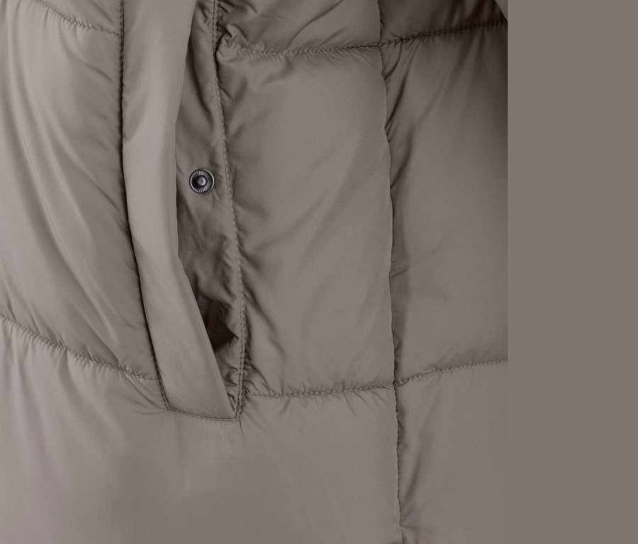 Egy taupe színű, steppelt kabát részlete kapucnival és zsebbel.