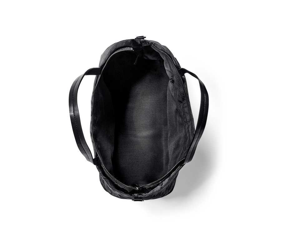 Egy üres, nyitott, fekete női shopper táska.