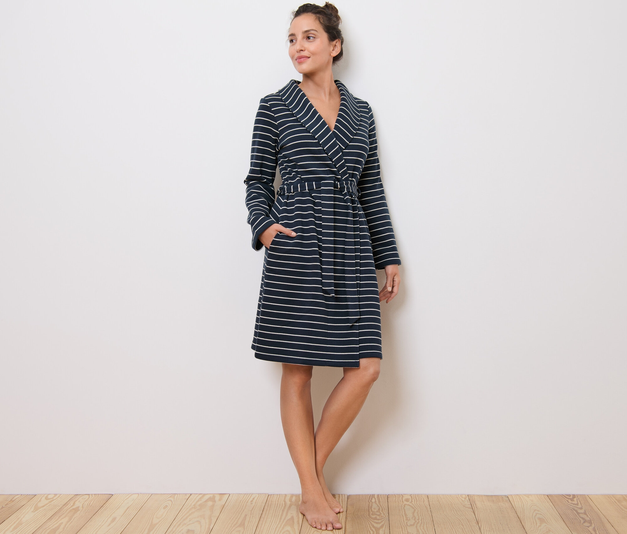 Nő áll, csíkos női köntöst visel.