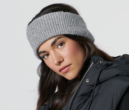 Nő kötött fejpántot és fekete mellényt visel.