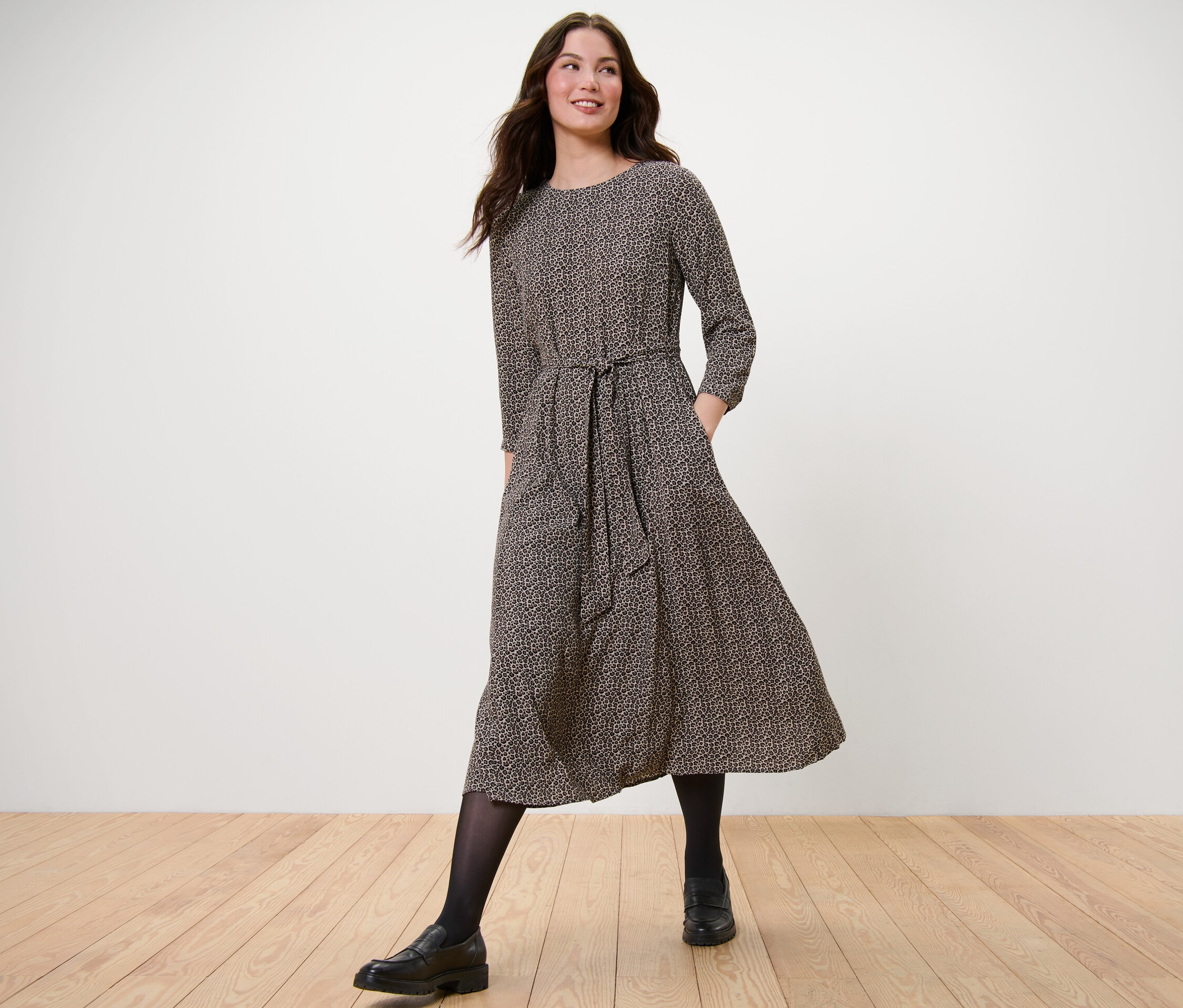 Nő sétál, és egy szövött, mintás midiruhát visel.