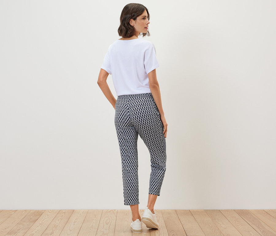 Hátulról látható nő fehér pólóban és mintás jersey nadrágban.