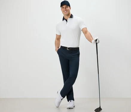 Egy férfi pózol egy golfütővel, és túranadrágot visel.