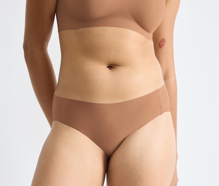 Nő törzse barna melltartót és egy barna sloggi ZERO Feel 2.0 High leg alsót visel.