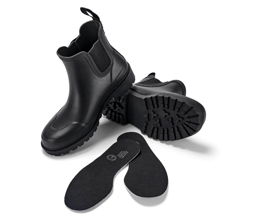 Két fekete csizma és két fekete cipőbetét fehér háttéren.