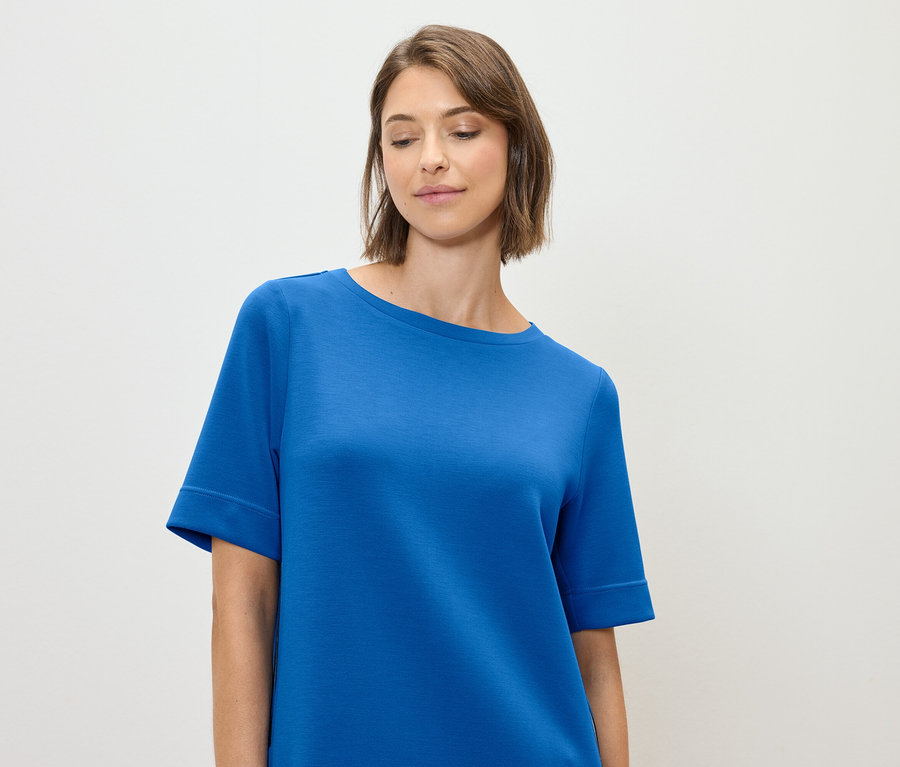 Nő kék pólót visel.