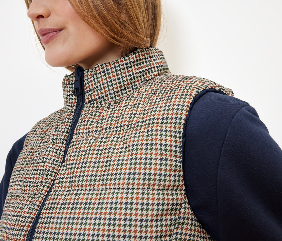 Egy női steppelt mellény részlete, kakasmintával és kék ujjakkal.