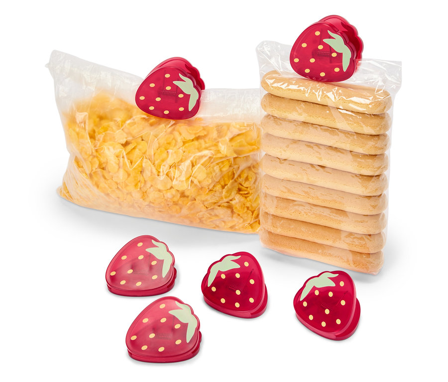 Egy zacskó kukoricapehely és egy csomag keksz van lezárva eper alakú csipeszekkel. További öt eper alakú csipesz van az előtérben.