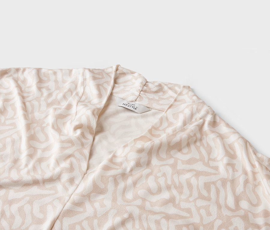 Egy világos színű, absztrakt mintás kabát közeli képe, 'MY STYLE' címkével.