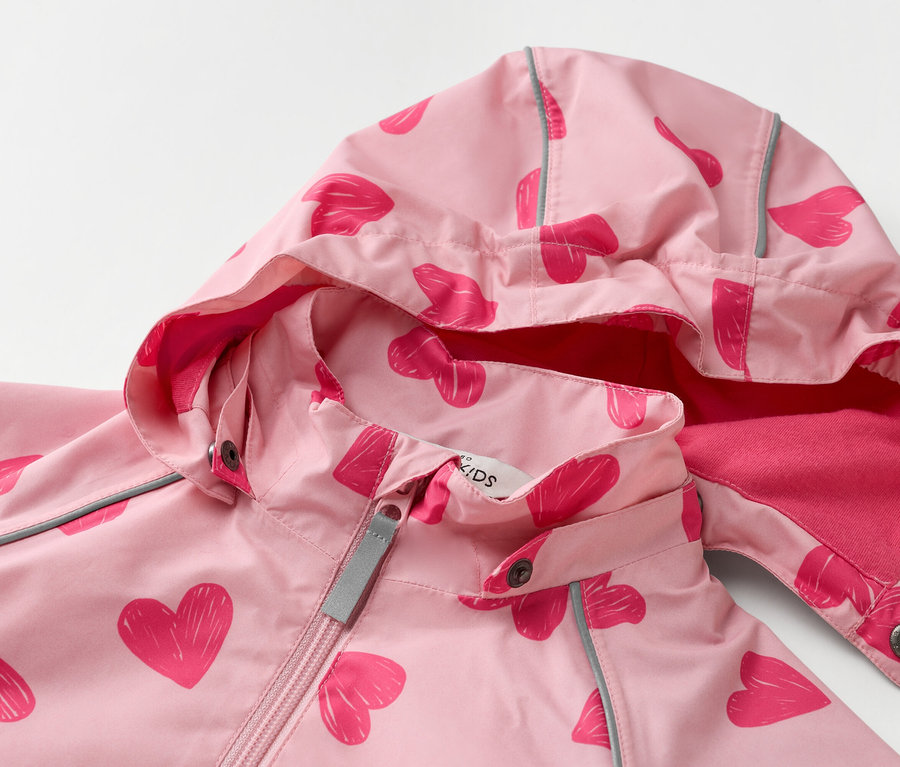 Egy világos rózsaszín, kapucnis gyerekdzseki közeli felvétele, sötét rózsaszín szívek mintájával.