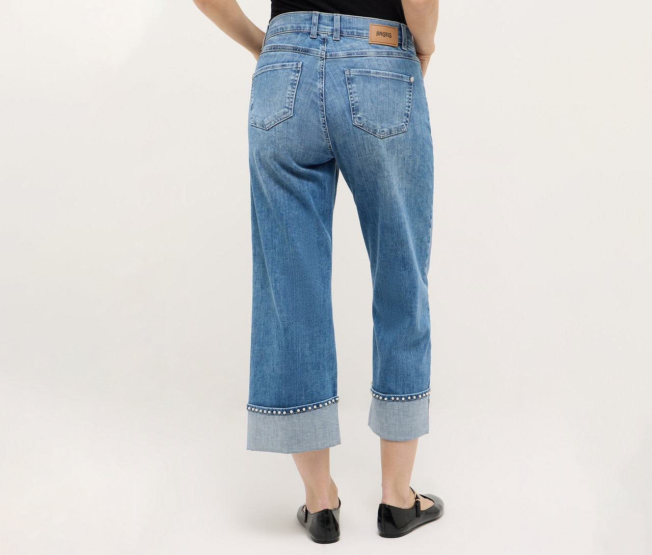 Hátulnézetből egy személy visel Angels denim »Linn Cool« farmert, fekete cipővel kombinálva, semleges háttér előtt.