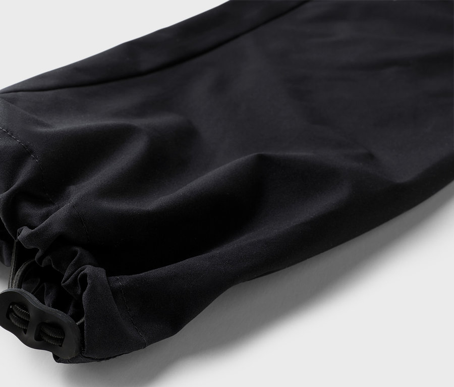 Egy fekete nadrágszár részletfotója, rugalmas szegéllyel és húzózsinórral.