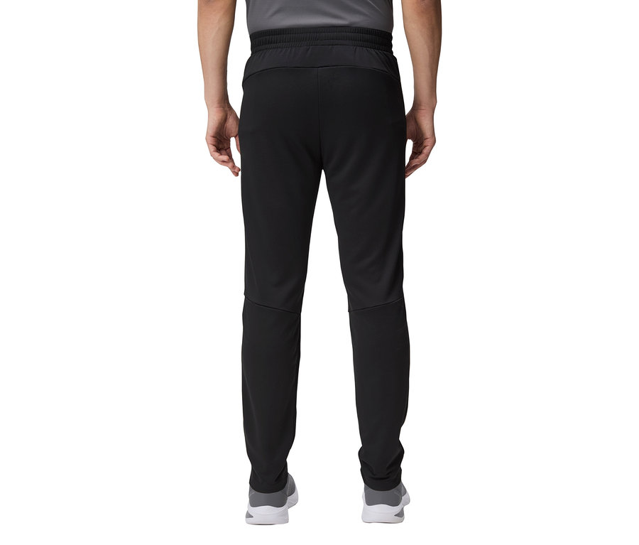 Közeli kép egy fekete melegítőnadrágot és szürke cipőt viselő személy hátuljáról.