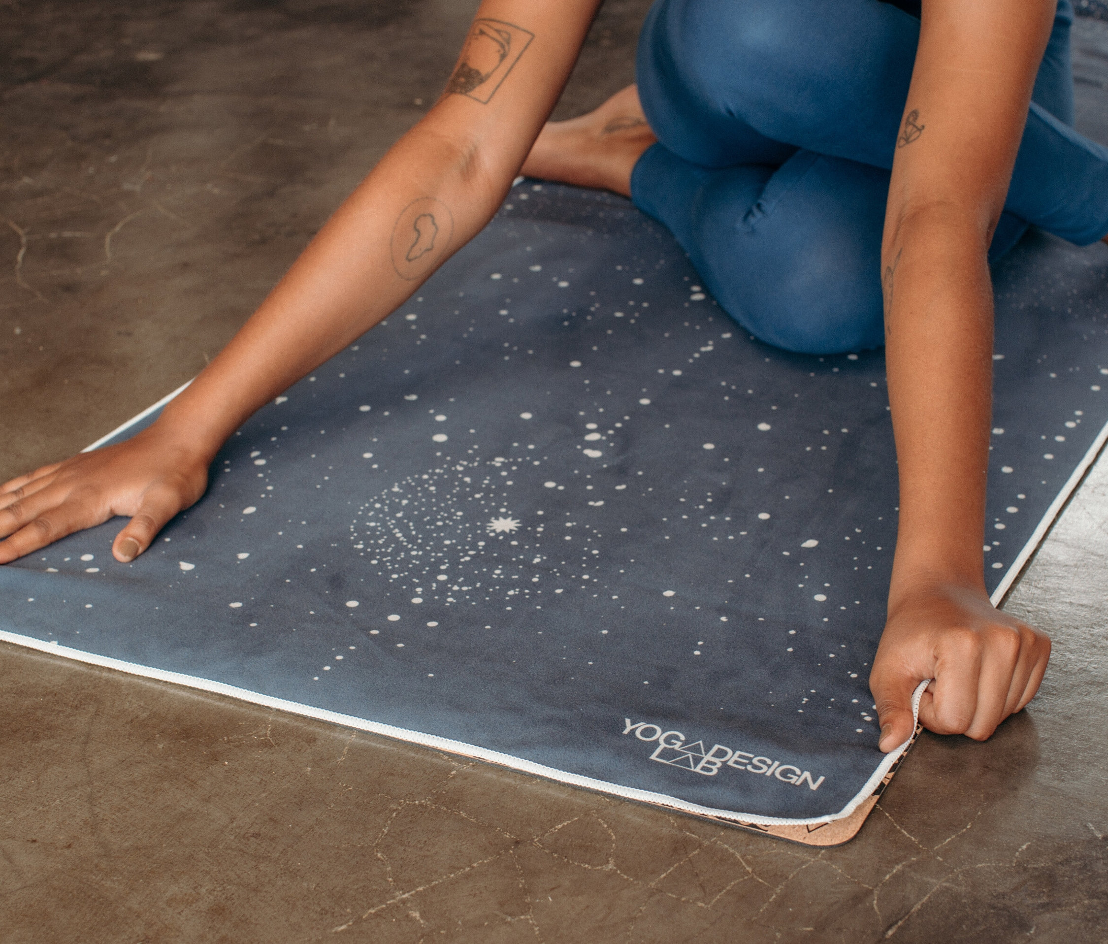 Nő ül egy csillagmintás jógaszőnyegen és megérinti a szélét.