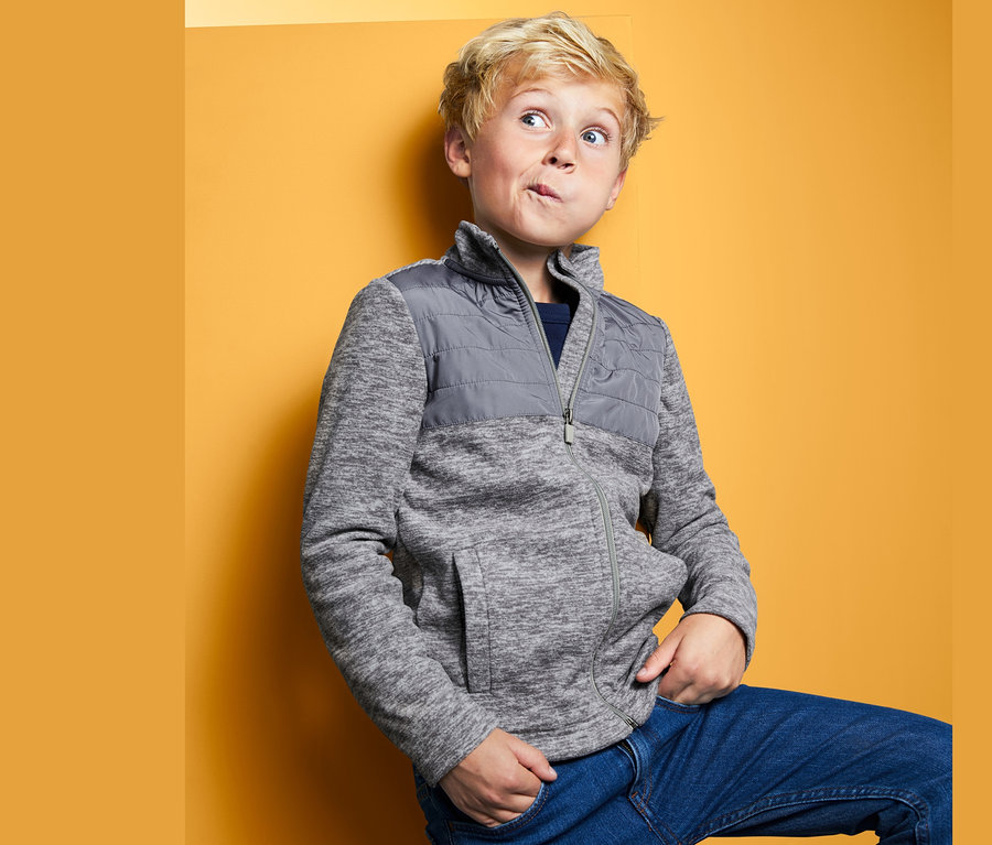 Fiú pózol fiú mikropolár felsőben sárga háttér előtt.