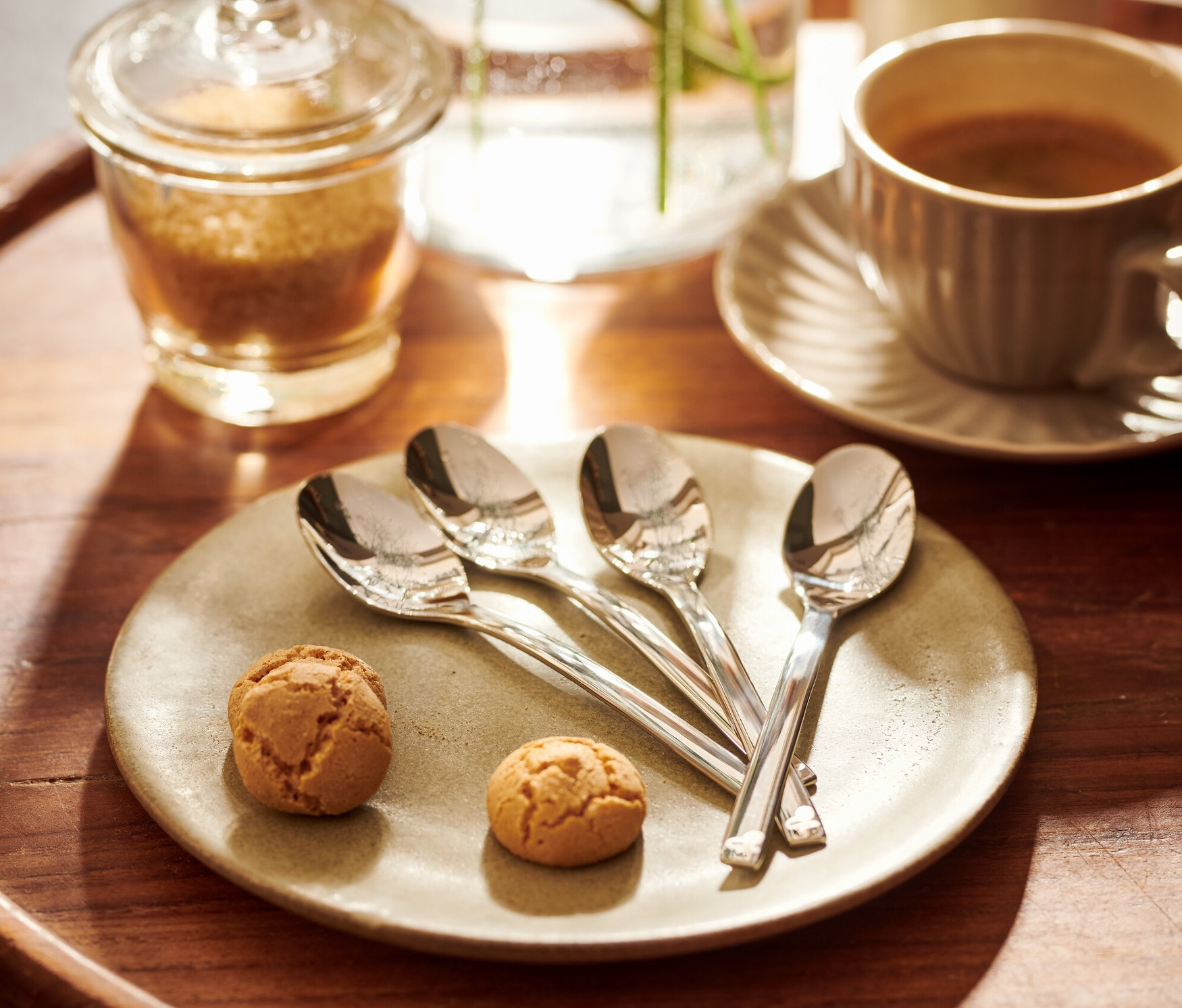 Egy fa tálcán 4 mokkáskanál van két keksz mellett egy tányéron.