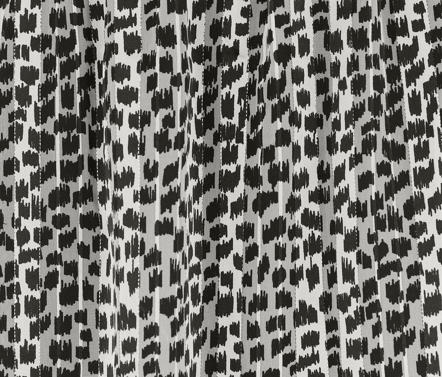 Egy aszimmetrikus szoknya részletgazdag képe, fekete mintával fehér alapon.