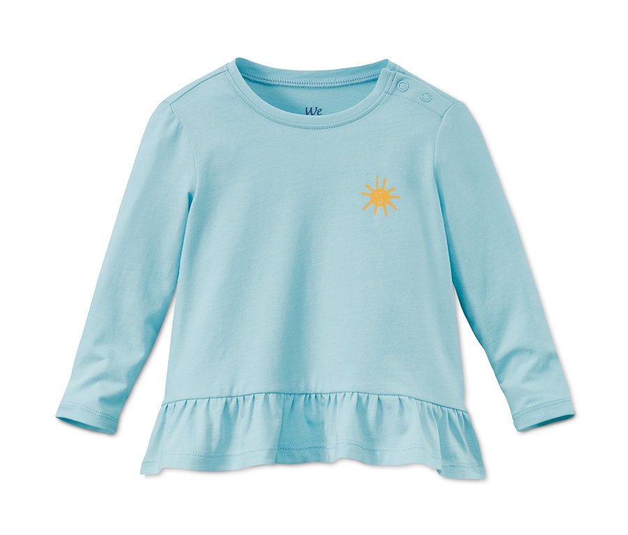 Egy világoskék, hosszú ujjú, bio pamut póló sárga nap mintával. A póló alja fodros.