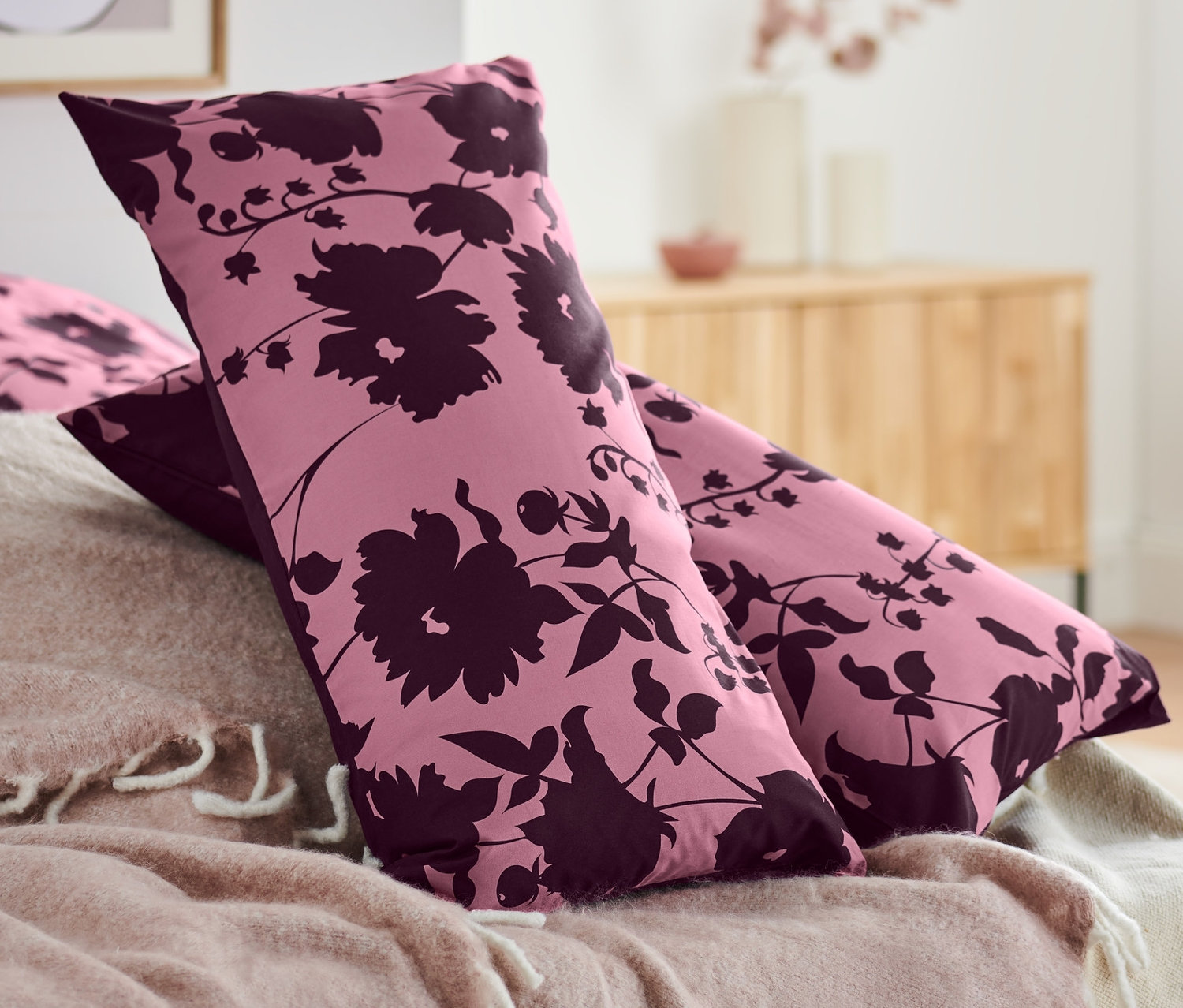 Virágmintás, lila, 2 db-os renforcé párnahuzat egy rózsaszín takaróval letakart ágyon.