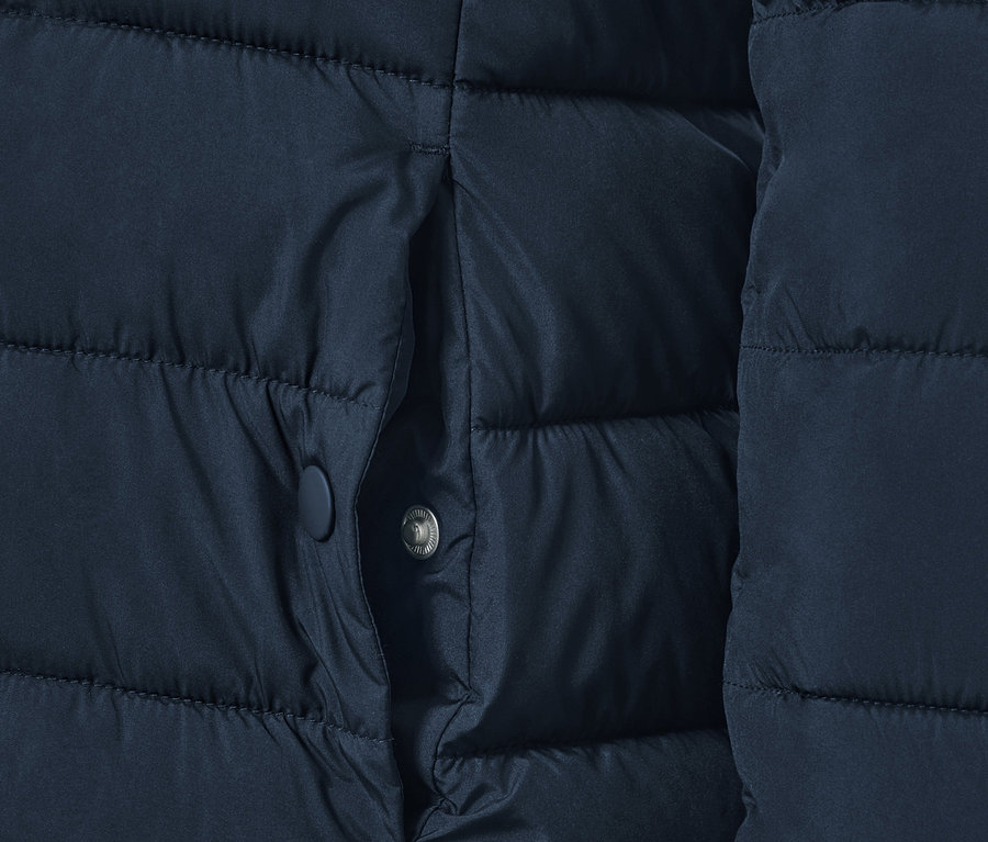 Egy sötétkék, steppelt dzseki részlete, zsebbel.