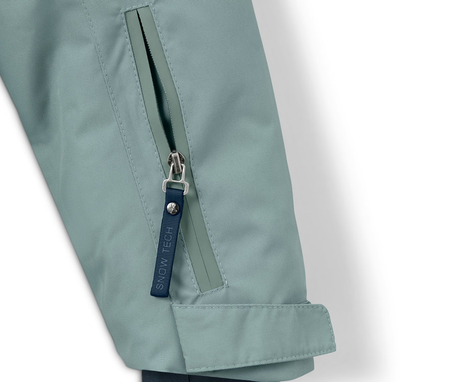 Egy fiú snowboard kabát részlete, sötétkék/zöld színben, cipzárral.