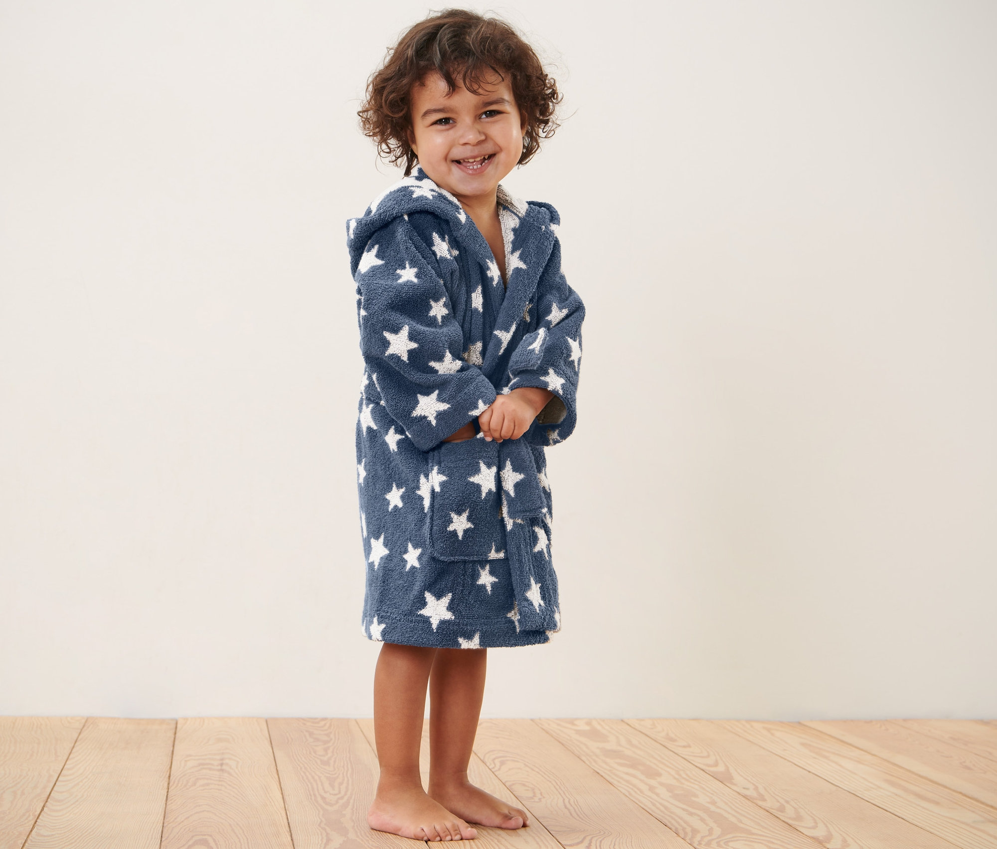 Egy gyermek áll és gyerek fürdőköpenyt visel.