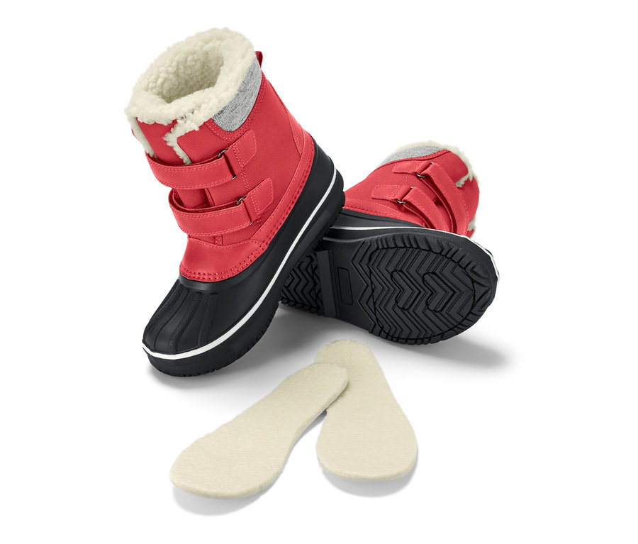 Egy piros gyerekcsizma az oldalán fekszik, mellette talpbetétek.