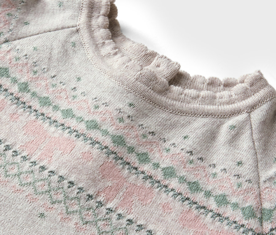 Egy rózsaszín és zöld mintás, fodros nyakú pulóver részlete.