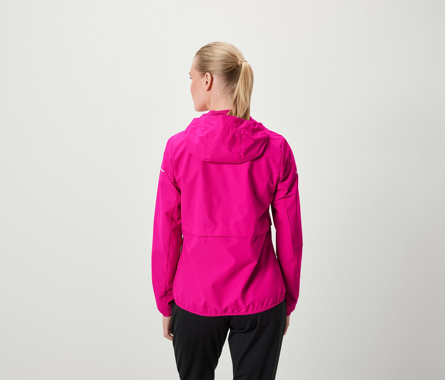 Hátulról látható egy szőke hajú, lófarokba kötött nő, aki rózsaszín kapucnis kabátot és fekete nadrágot visel.