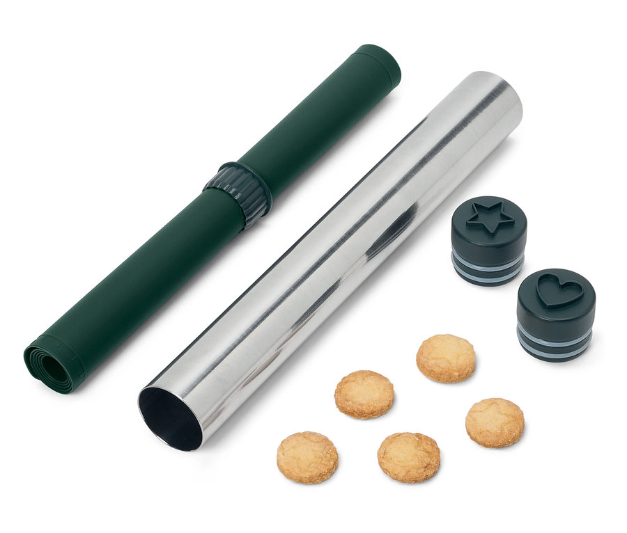 Egy zöld sodró alátét és egy ezüst színű nyújtóhenger csillag és szív alakú süteménykiszúrókkal és kekszekkel.