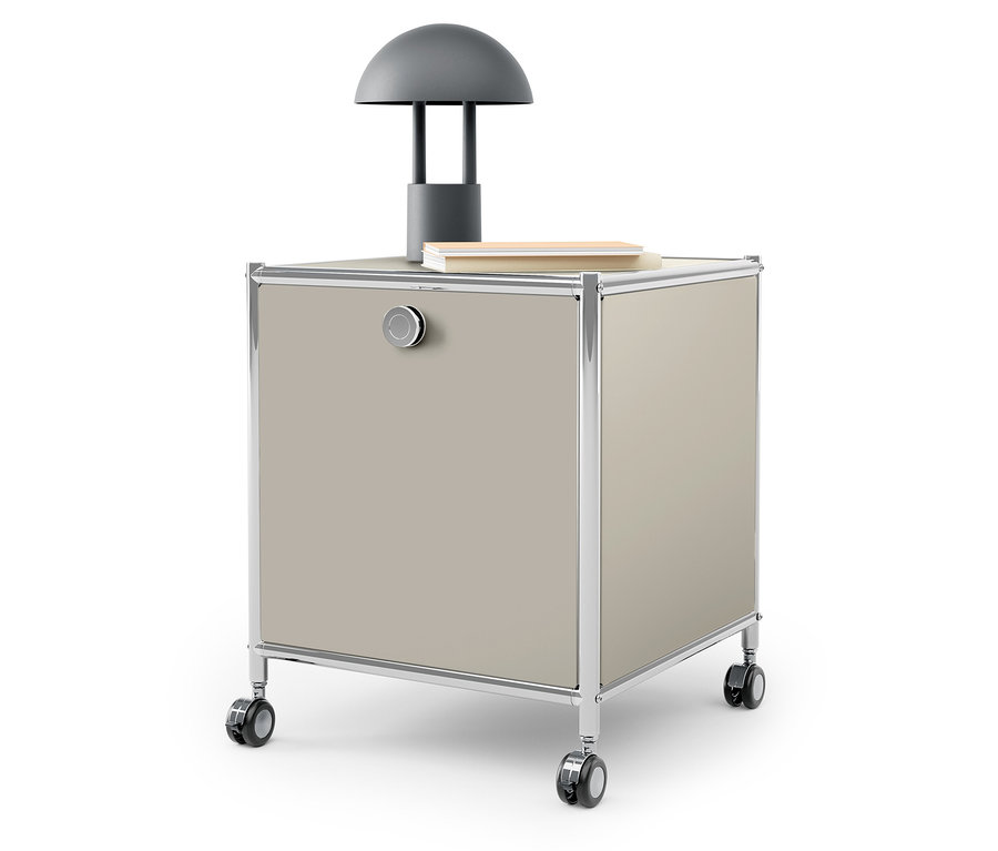 Egy bézs színű, görgős konténer tetején egy szürke lámpa és egy könyv található.